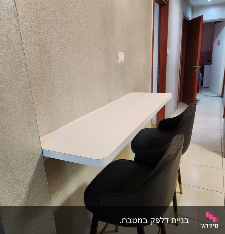 דלפק לבן עם שני כיסאות בר שחורים במטבח